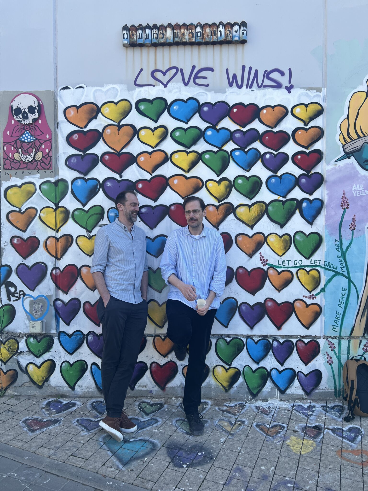 Street Art, viele bunte Herzen, „Love wins“, Michael und Jochen stehenm davor