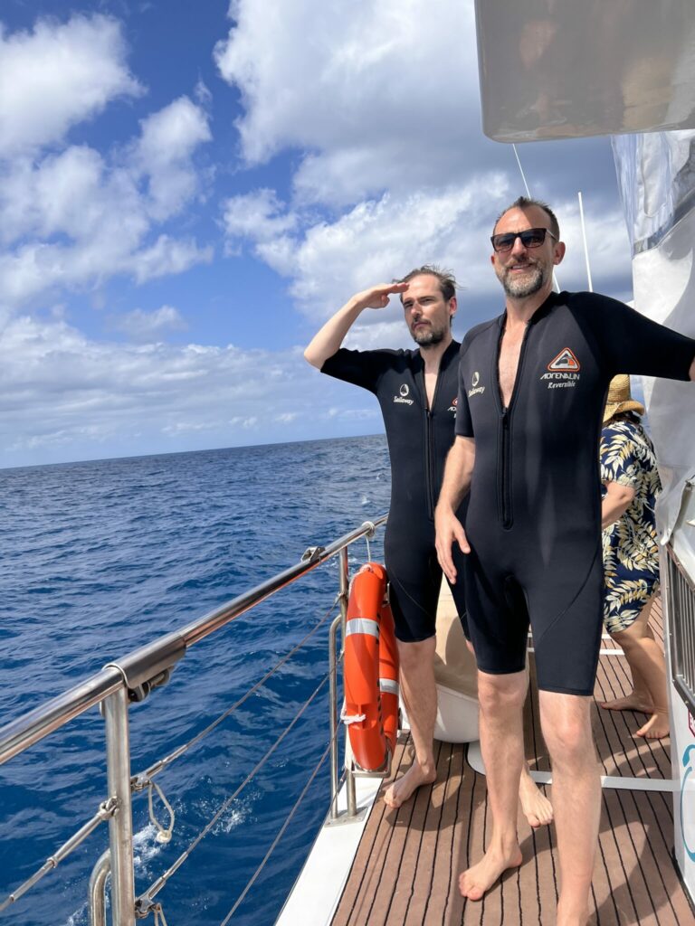 Michael und Jochen in zu kleinen Taucheranzügen auf dem Weg zum Great Barrier Reef auf einem Boot, Queensland, Australien