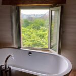 Freistehende Badewanne am Fenster mit Blick in die Natur